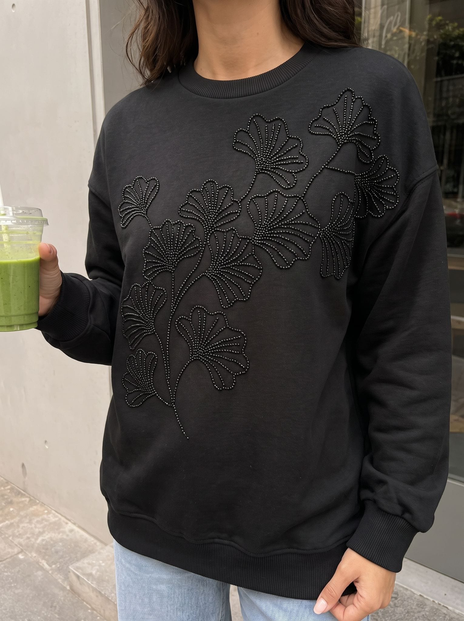 Tone-on-tone ginkgo leaf embroidery on a black sweatshirt.