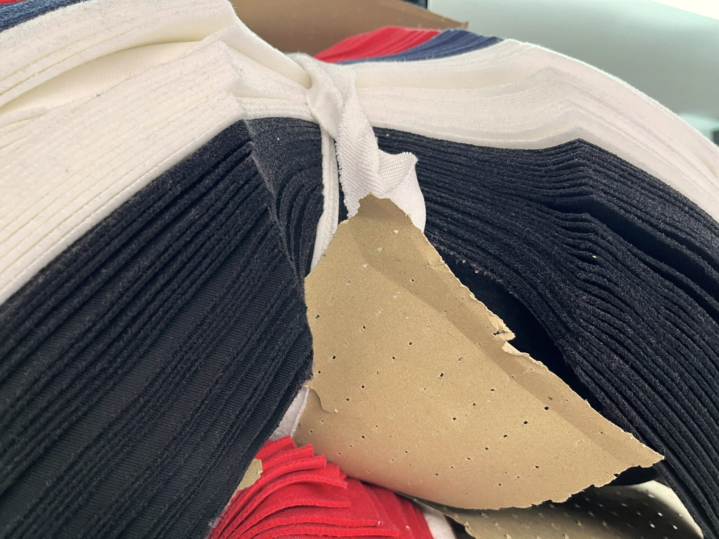 Stacks of cut navy, white and red pieces with a perforated pattern sheet.