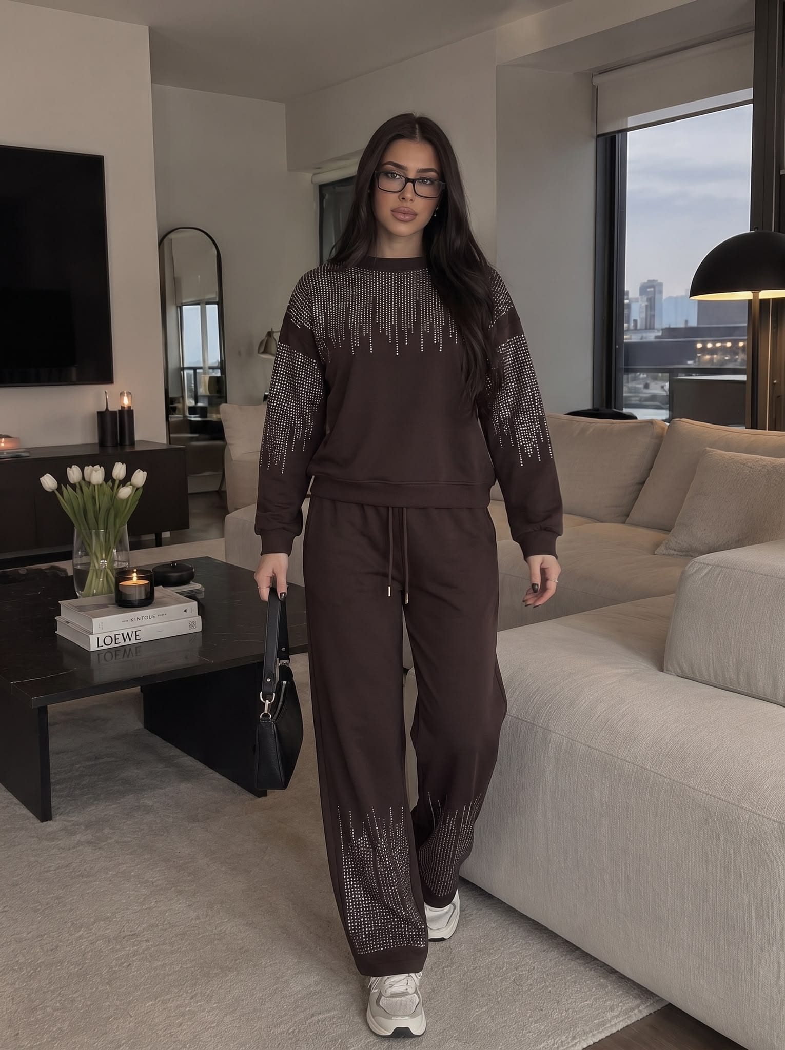 Model walking through a living room in a brown rhinestone-embellished set.